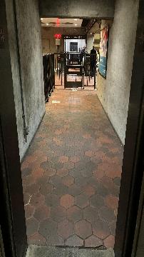 A picture of the path out of the elevator on the mezzanine level towards guide rails. There are walls close in on both sides of the path.