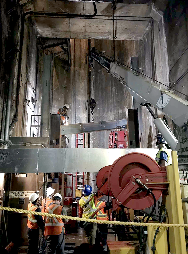To start construction of the steel “second floor” across both tracks, workers installed the first beams at the base of a deep vertical shaft away from the tracks. Each steel beam was carefully moved from the flatcar to its overhead location.