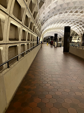 A picture of the path towards the Green and Yellow line tracks. There is a wall to the left of the picture and to the right there are some disconnected walls with large pylon displays.